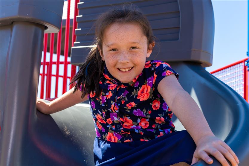 A girl smiles while going down a slide